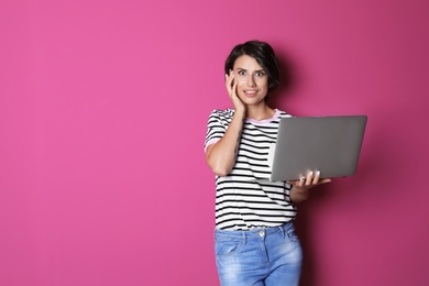 Photo of Young woman with modern laptop on color background