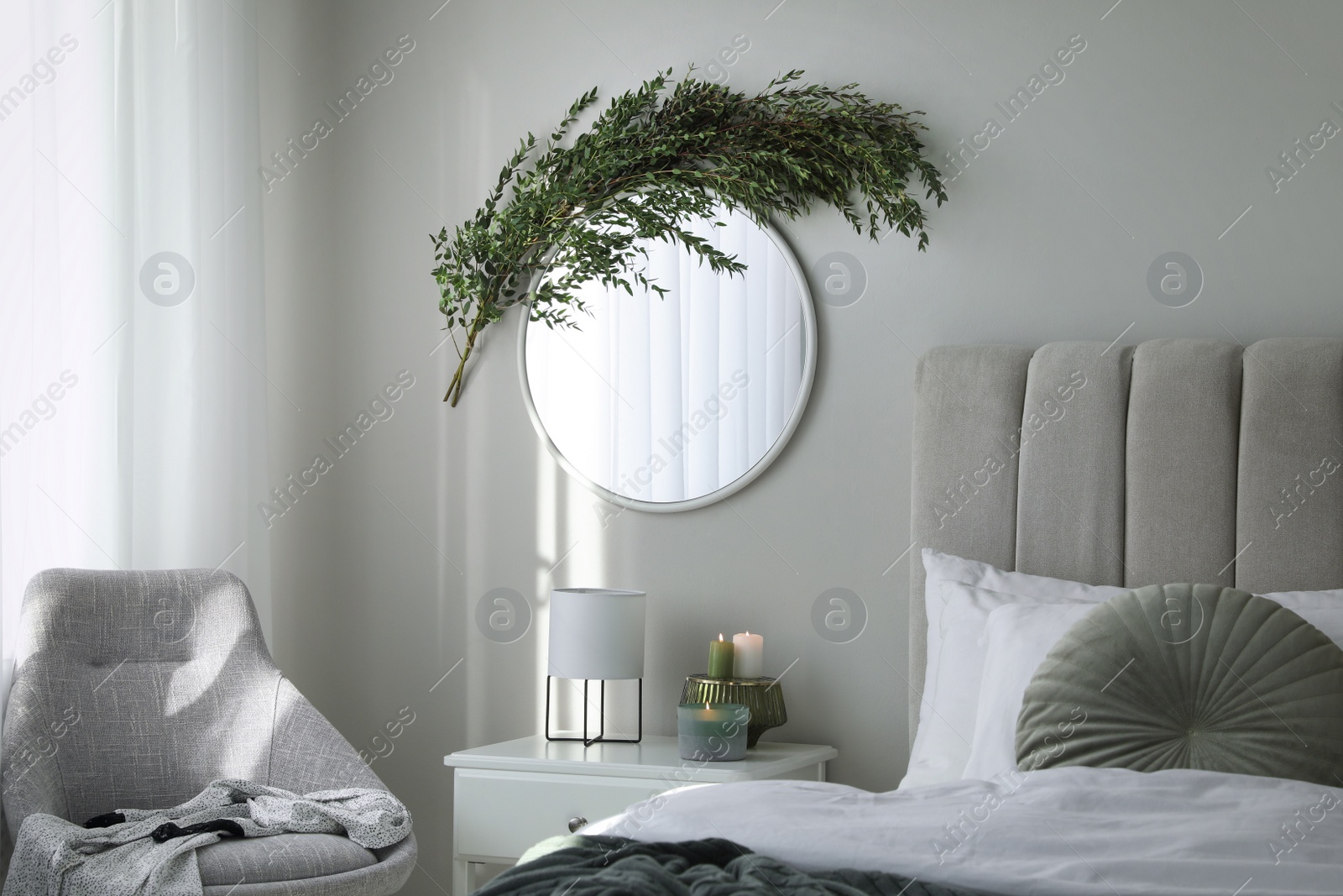 Photo of Stylish mirror decorated with green eucalyptus in bedroom