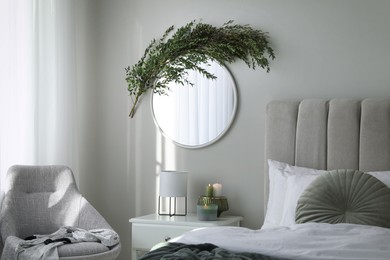 Stylish mirror decorated with green eucalyptus in bedroom