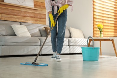 Photo of Woman cleaning floor with mop at home, closeup
