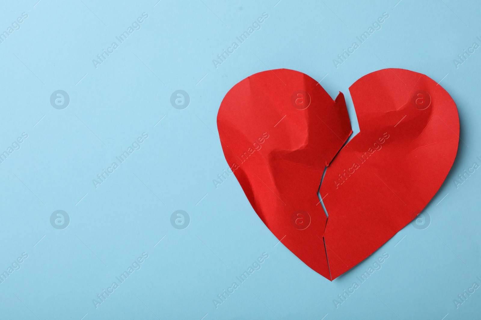 Photo of Torn paper heart on light blue background, top view with space for text. Relationship problems concept