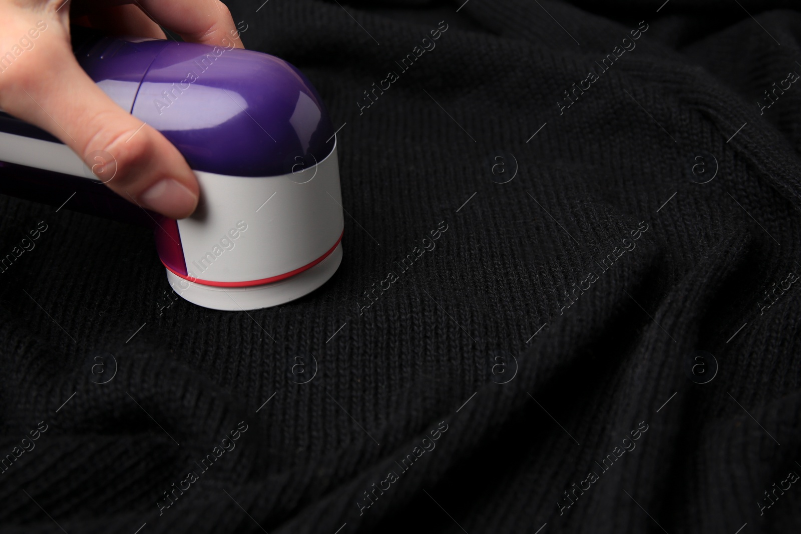 Photo of Woman using fabric shaver on black cloth with lint, closeup. Space for text