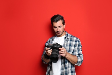 Photo of Young photographer with professional camera on red background