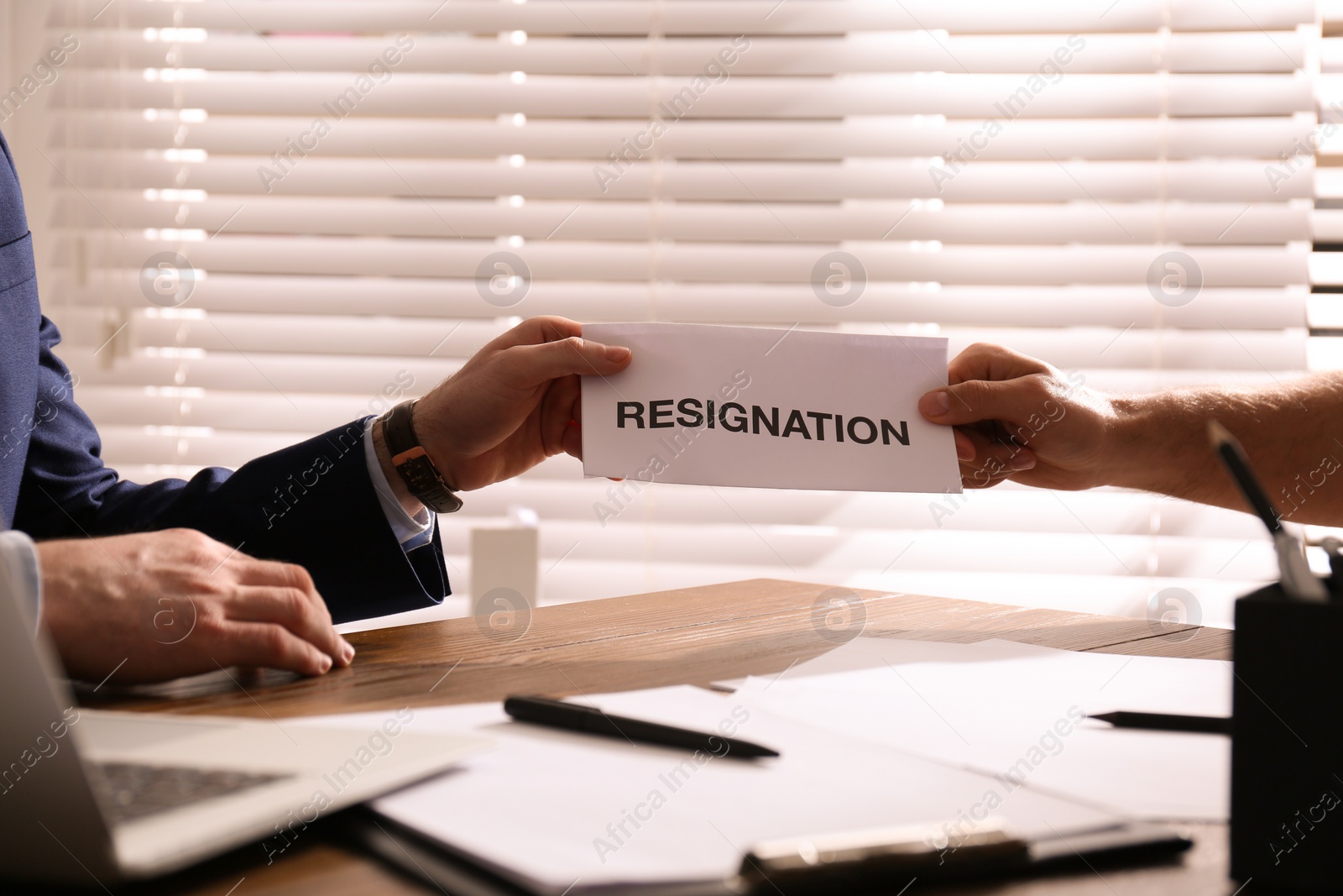 Photo of Employee giving resignation letter to boss in office, closeup