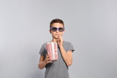 Photo of Boy with 3D glasses and popcorn during cinema show on grey background