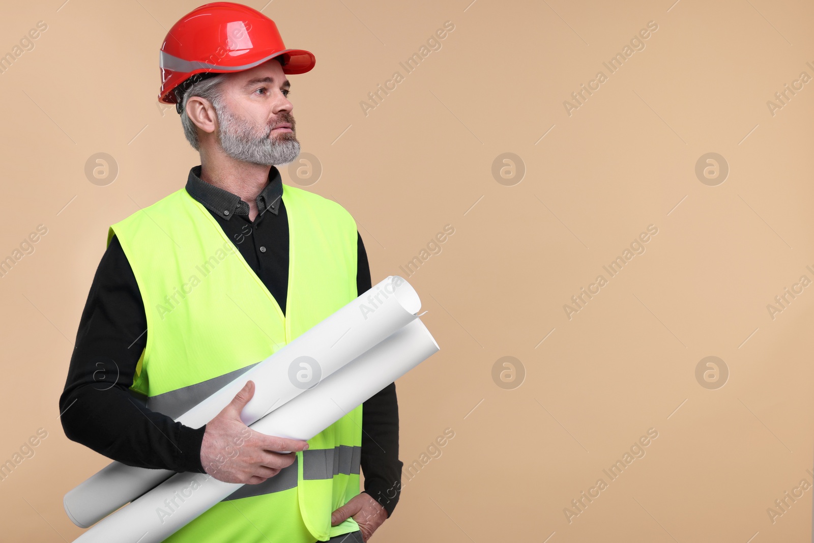 Photo of Architect in hard hat holding drafts on beige background. Space for text