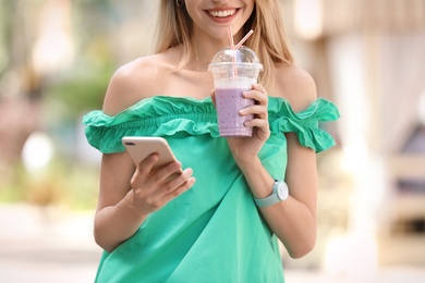 Young woman with plastic cup of healthy smoothie outdoors