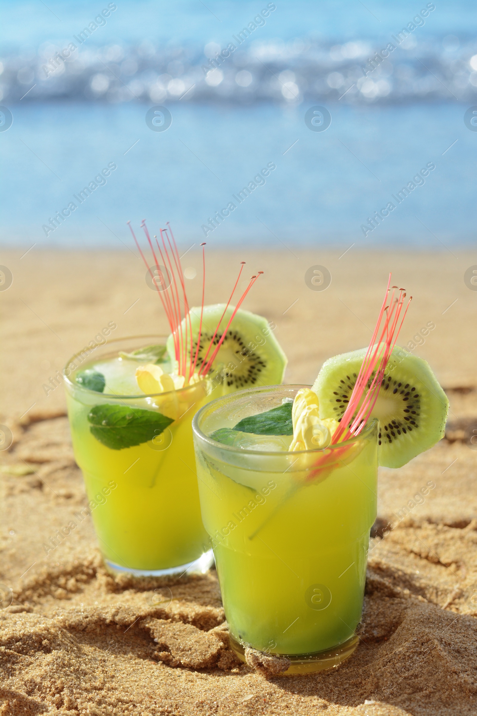 Glasses of refreshing drink with kiwi and mint on sand near sea. Space for text Photo of Glasses of refreshing drink with kiwi and mint on sand near sea. Space for text