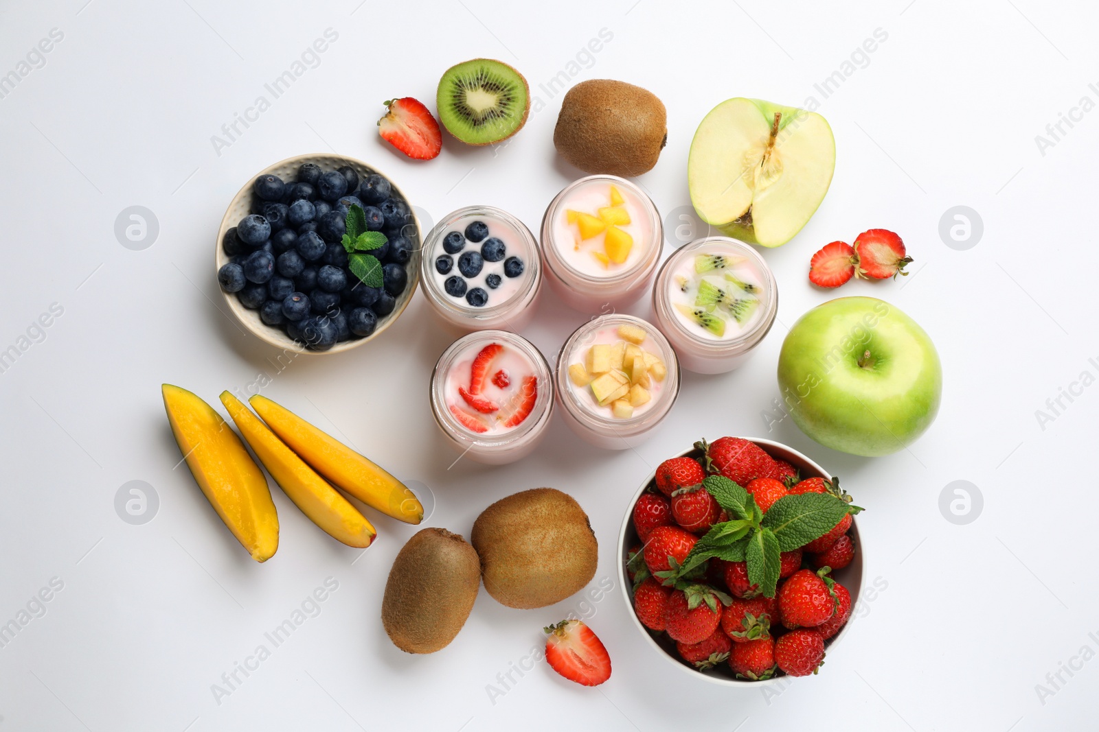 Photo of Tasty yogurt in glass jars and ingredients on white background, top view