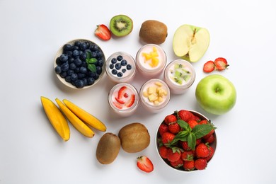 Photo of Tasty yogurt in glass jars and ingredients on white background, top view