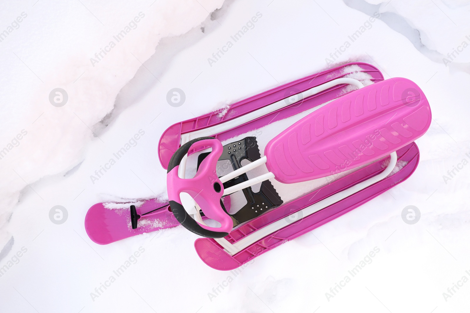 Photo of Stylish pink snow-scooter outdoors, top view. Winter season