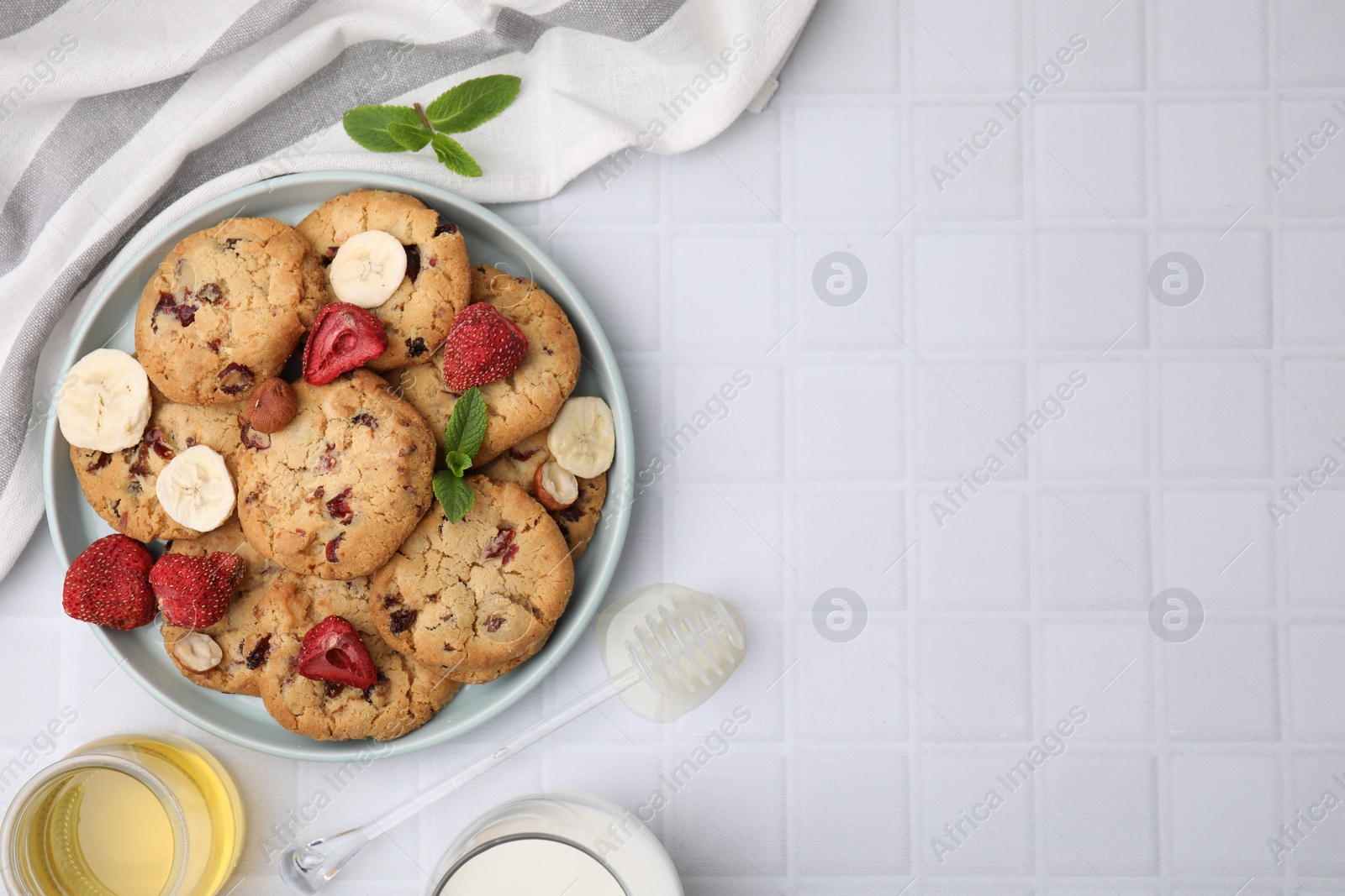 Cookies with freeze dried fruits, mint, milk, honey and nuts on white tiled table, flat lay. Space for text Photo of Cookies with freeze dried fruits, mint, milk, honey and nuts on white tiled table, flat lay. Space for text