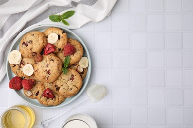 Photo of Cookies with freeze dried fruits, mint, milk, honey and nuts on white tiled table, flat lay. Space for text