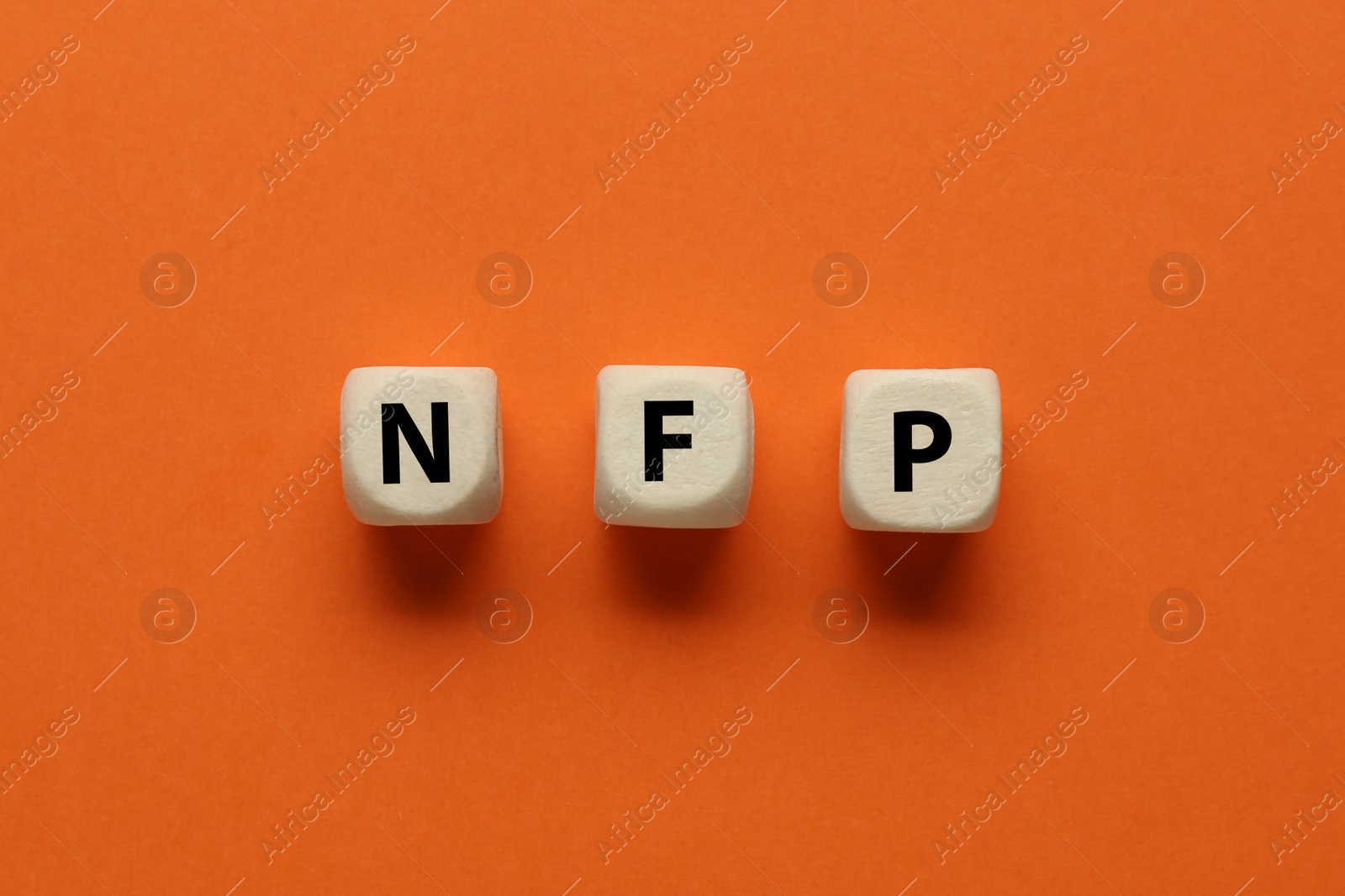 Photo of Abbreviation NFP (Nonfarm Payroll) made of cubes with letters on orange background, flat lay