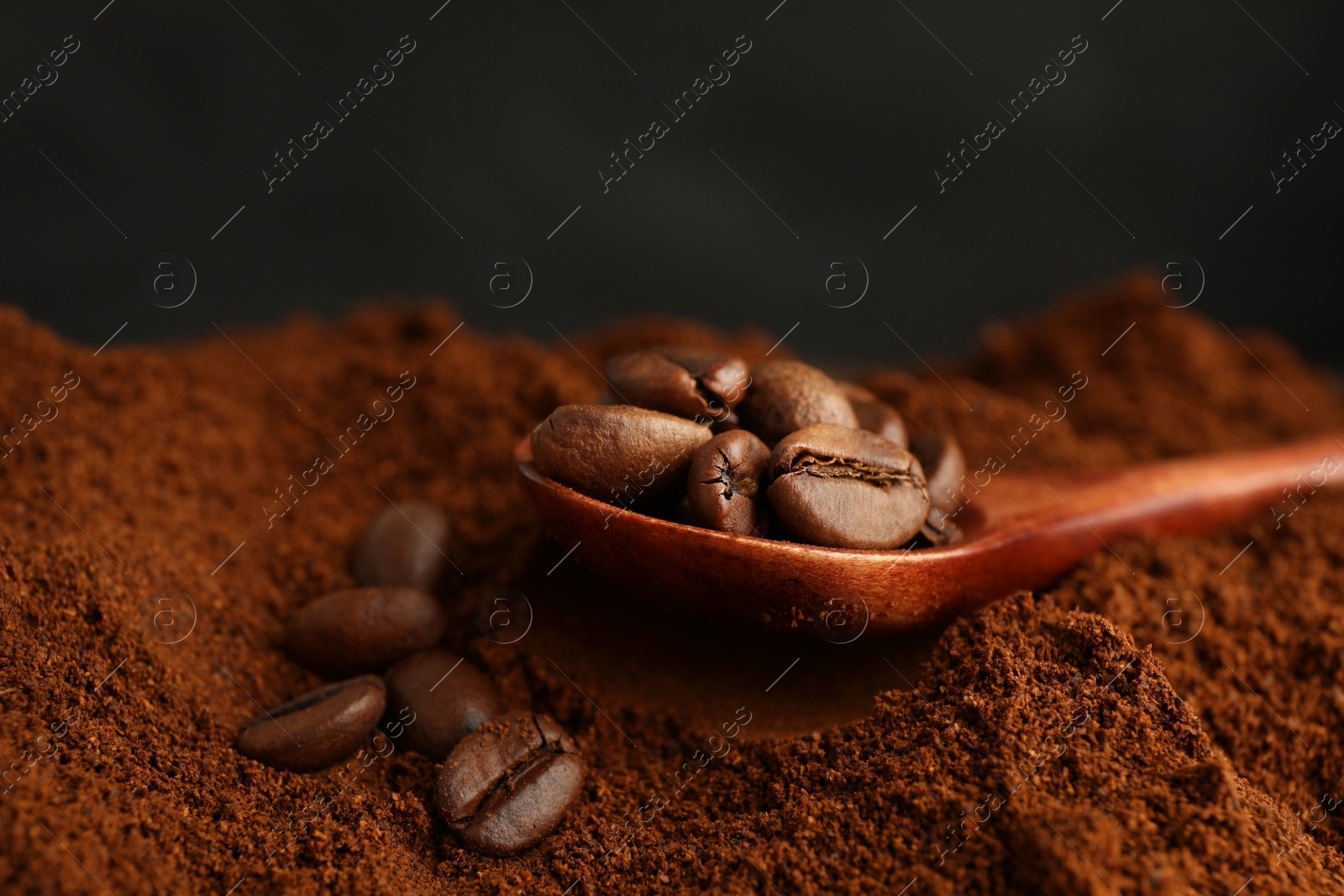 Photo of Coffee grounds and roasted beans on dark background, closeup