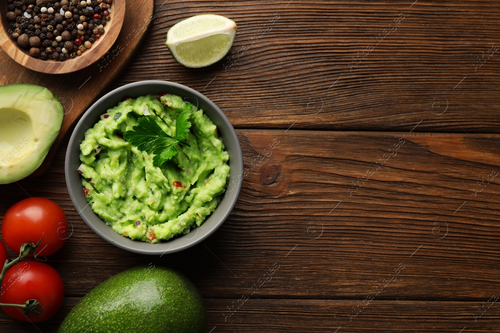 Photo of Delicious guacamole and ingredients on wooden table, flat lay. Space for text