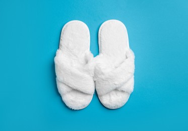 Photo of Pair of soft fluffy slippers on blue background, top view