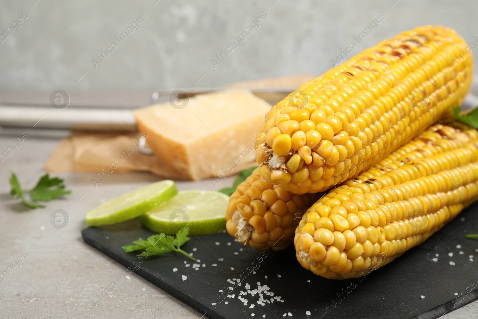 Photo of Delicious grilled corn cobs on grey table. Space for text