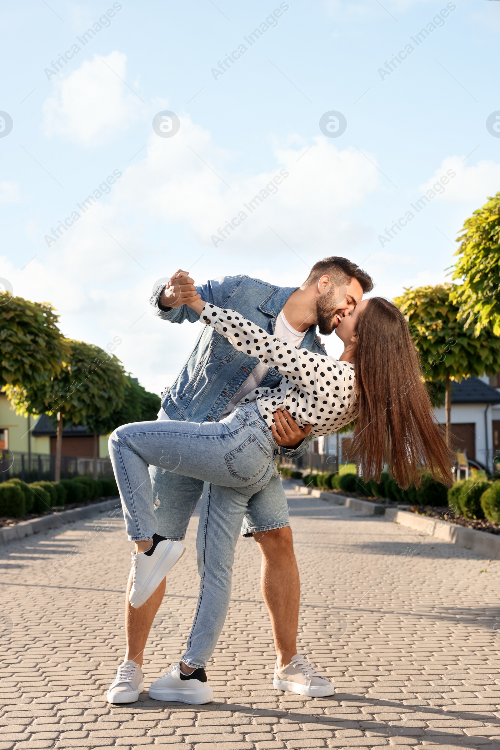 Photo of Happy couple dancing and kissing outdoors on sunny day