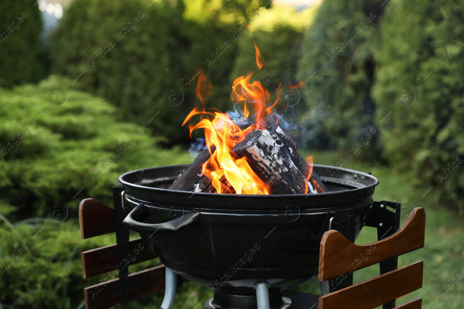 Photo of Portable barbecue grill with fire flames outdoors, closeup