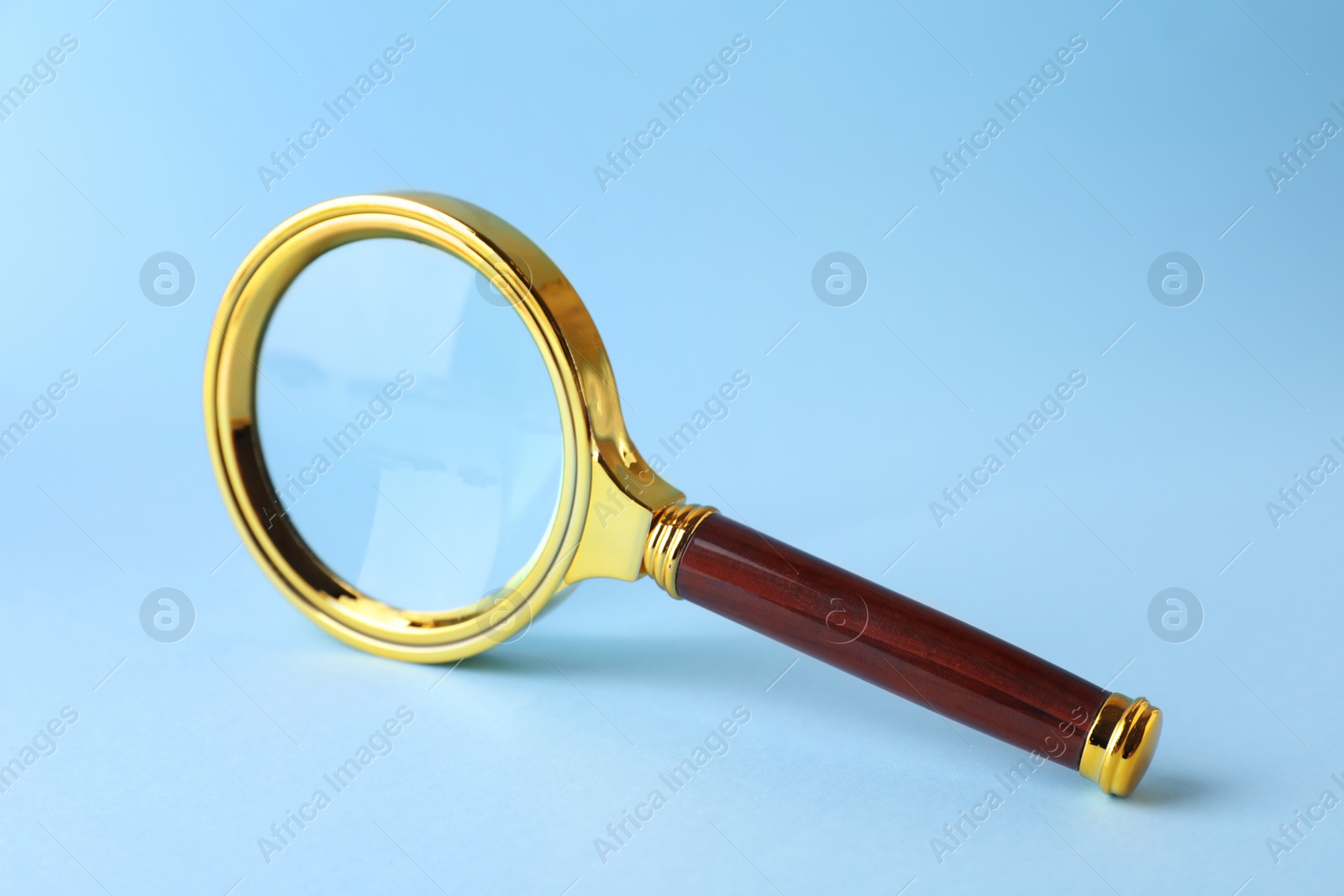 Photo of Magnifying glass with handle on light blue background