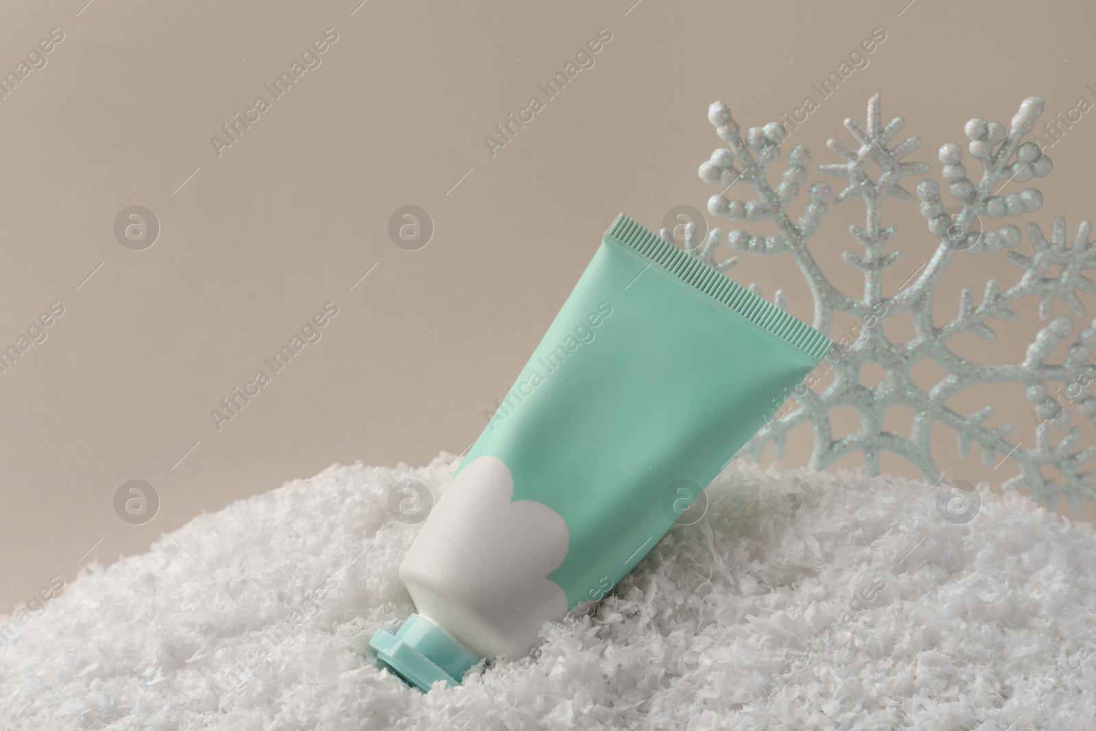 Winter skin care. Hand cream and decorative snowflake on artificial snow against light grey background, space for text Photo of Winter skin care. Hand cream and decorative snowflake on artificial snow against light grey background, space for text