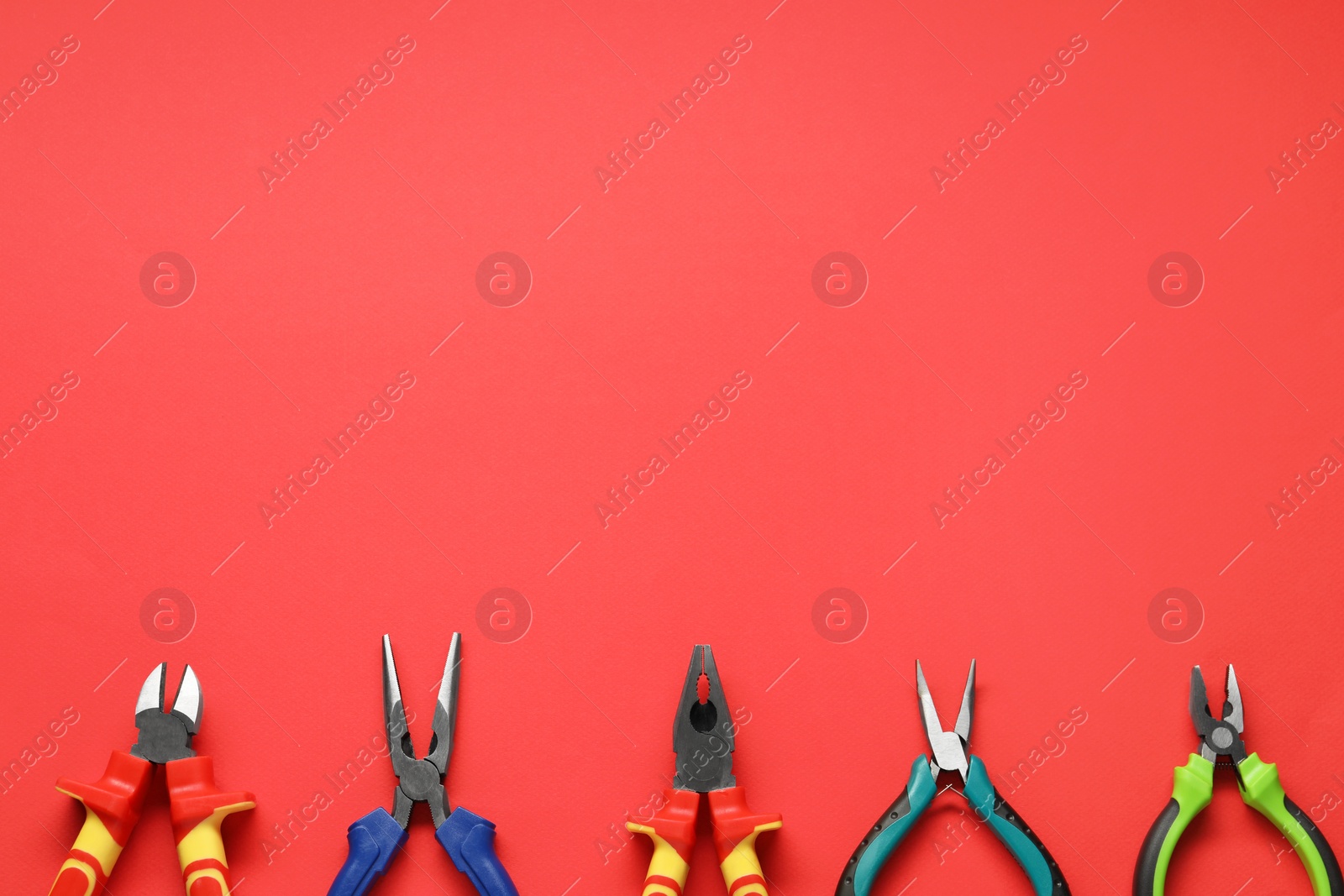 Photo of Different pliers on red background, flat lay. Space for text