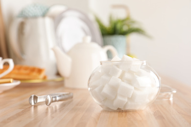 Photo of Glass bowl with white sugar cubes on wooden table