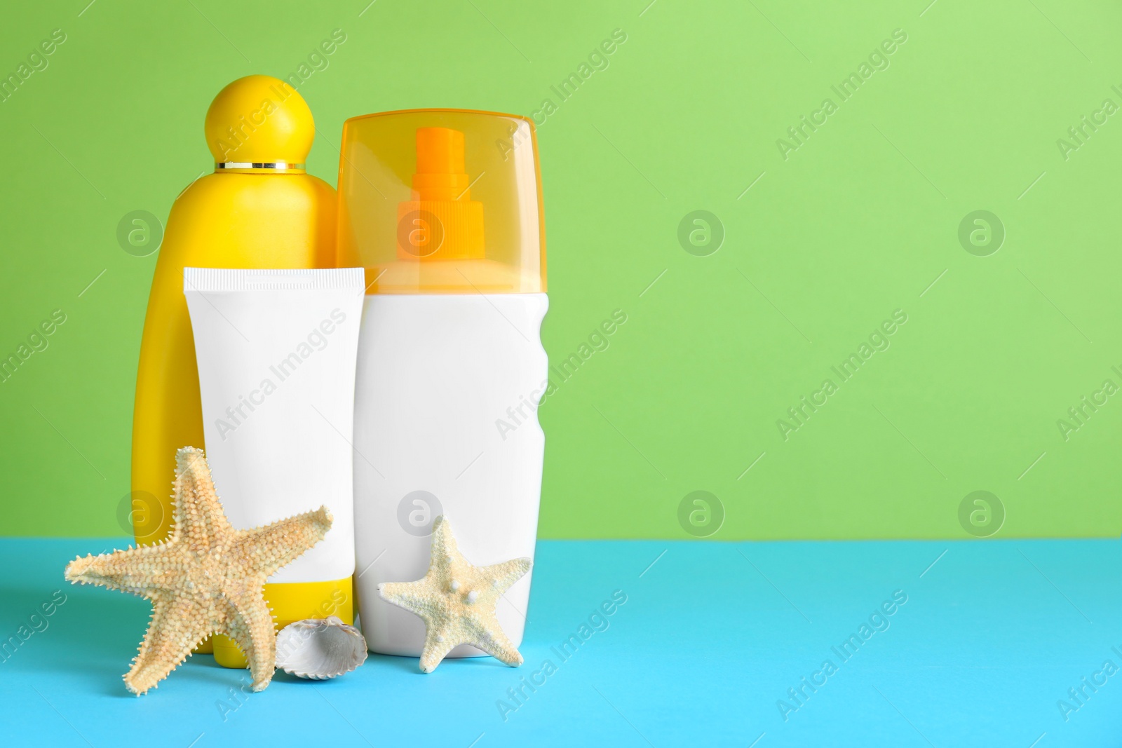 Photo of Different suntan products and starfishes on color background. Space for text