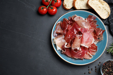 Photo of Tasty prosciutto served on black table, flat lay. Space for text