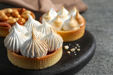 Photo of Different tartlets on grey table, closeup. Tasty dessert