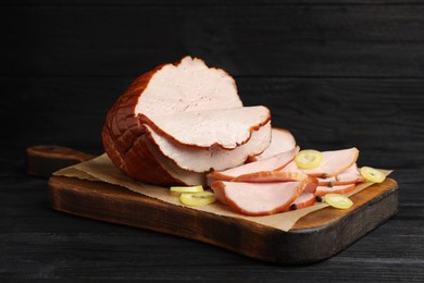 Photo of Delicious cut ham served on black wooden table