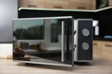 Photo of Open modern microwave oven on table in kitchen