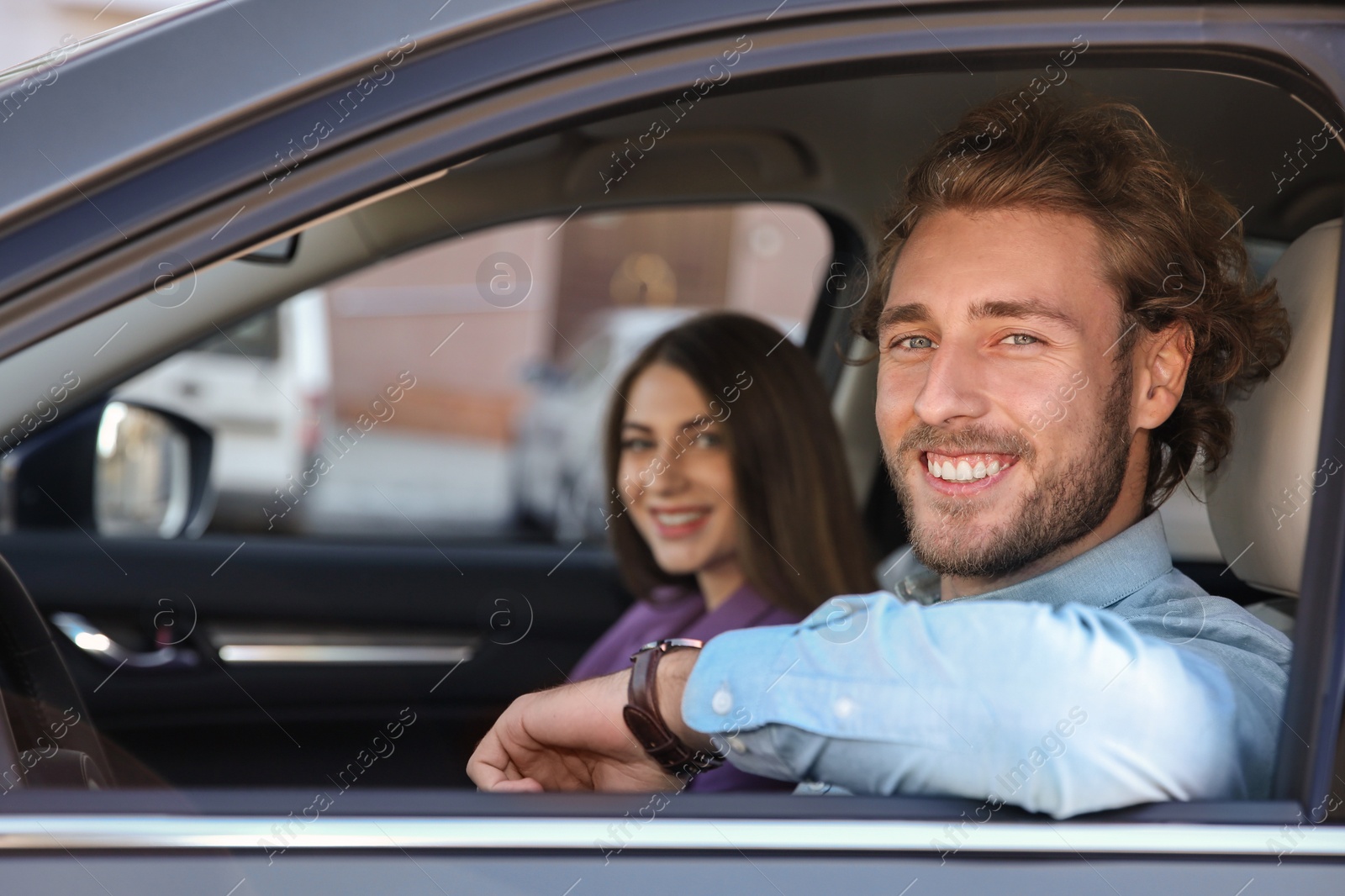 Photo of Happy young man and woman in modern car