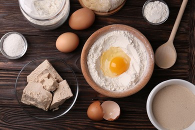 Photo of Different types of yeast, eggs, salt, dough and flour on wooden table, flat lay
