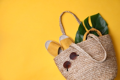 Photo of Stylish straw bag and summer accessories on yellow background, flat lay. Space for text