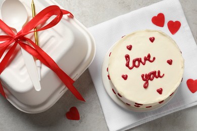 Bento cake with text Love You, takeaway packaging and gift box on grey table, flat lay. St. Valentine's day surprise