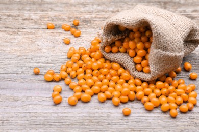 Sack with fresh ripe sea buckthorn berries on wooden table, space for text