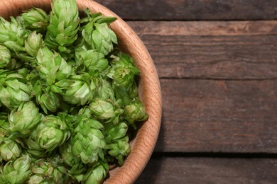 Bowl of fresh green hops on wooden table, top view. Space for text