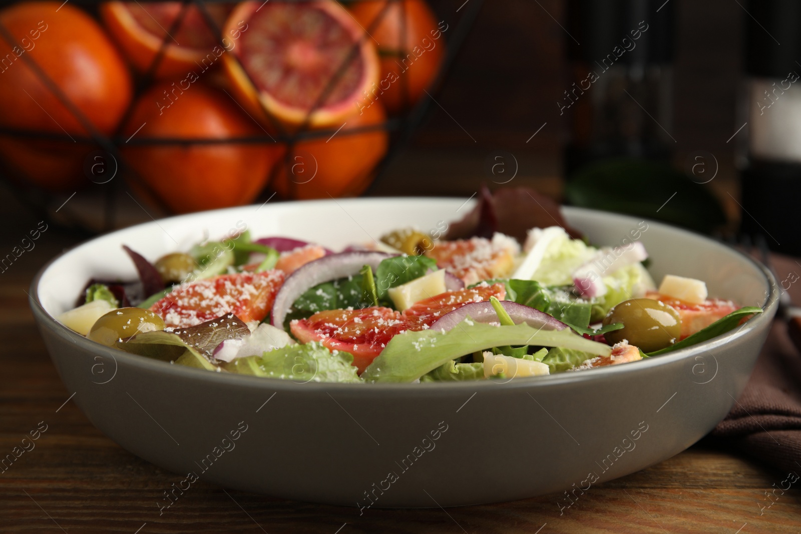 Photo of Bowl of delicious sicilian orange salad on wooden table, closeup