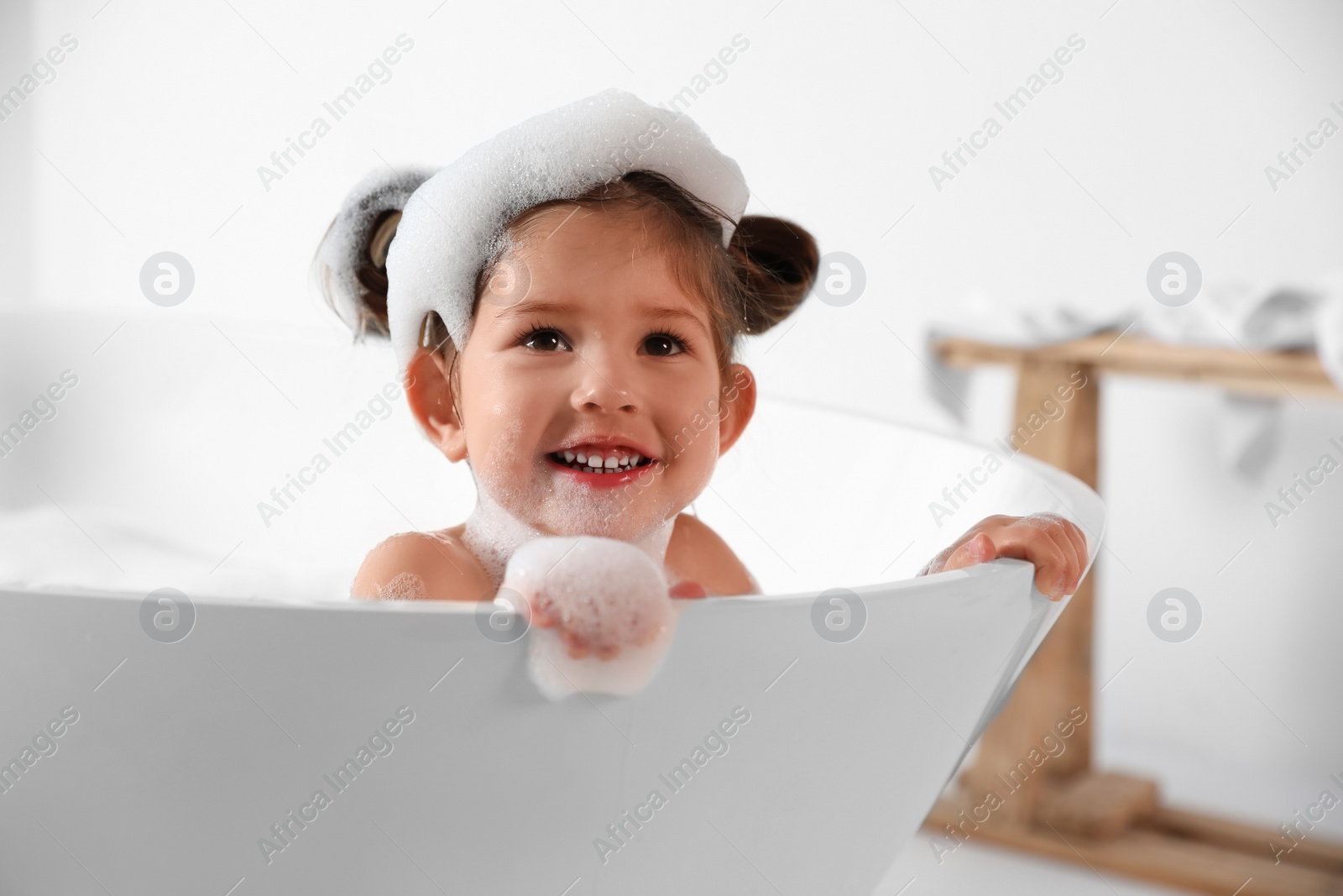 Photo of Cute little girl taking bubble bath at home