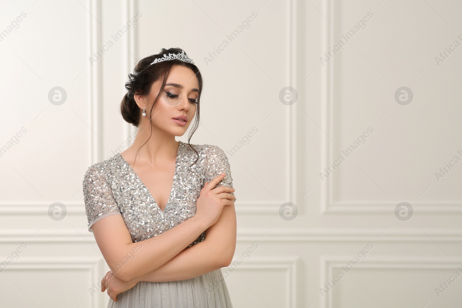 Photo of Beautiful young woman wearing luxurious tiara indoors, space for text