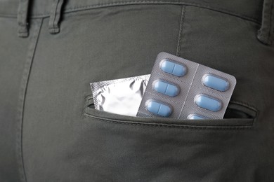 Jeans with pills and condom in pocket, closeup. Potency problem