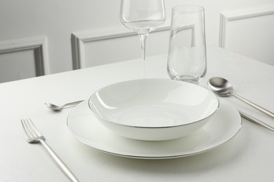 Photo of Stylish setting with cutlery and glasses on white textured table