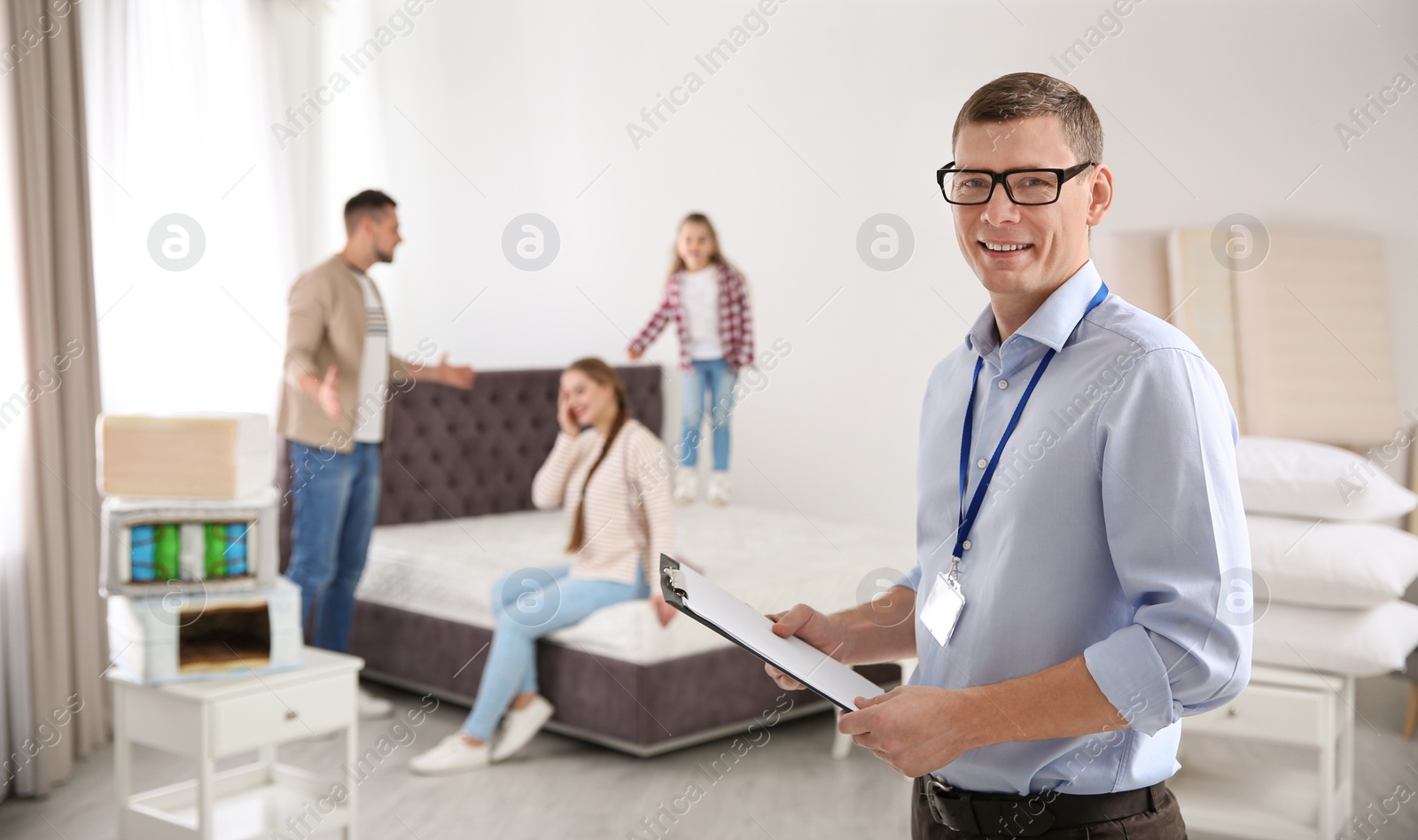 Photo of Happy salesman and his clients in mattress store