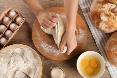 Female baker preparing bread dough at kitchen table, top view