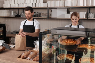 Two happy sellers working in bakery shop