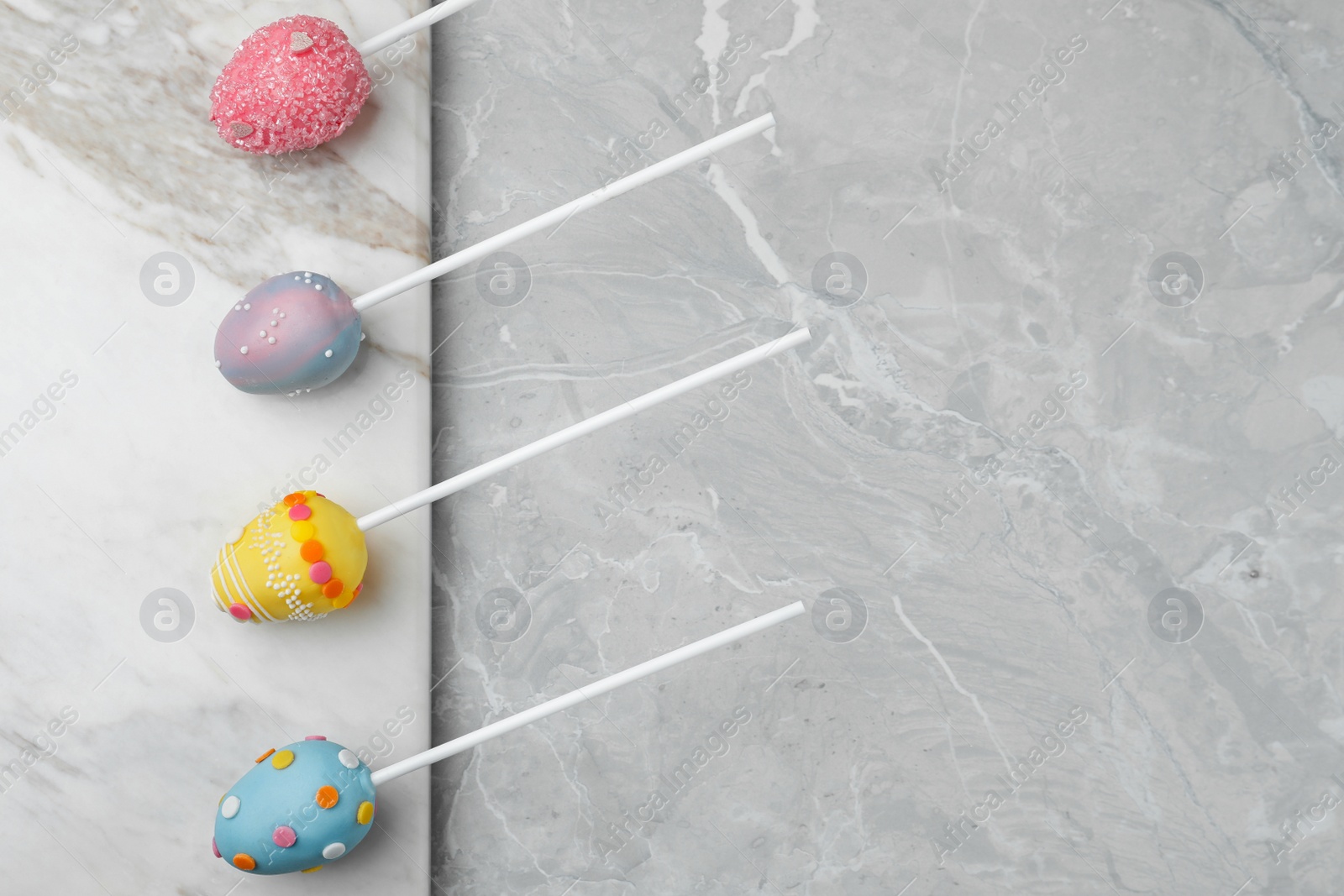 Photo of Egg shaped cake pops and space for text on grey marble table, flat lay. Easter celebration