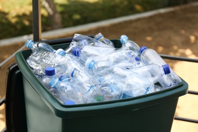 Many used plastic bottles in trash bin outdoors, closeup. Recycling problem