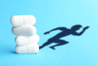 Image of Doping concept. White pills and silhouette of sportsman on turquoise background